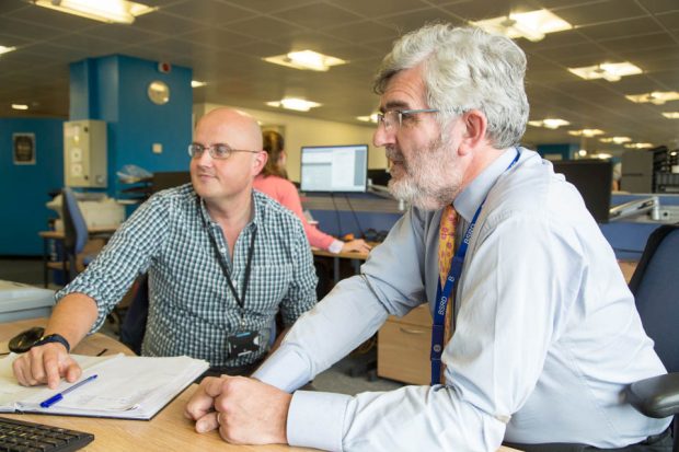 Wyn Parry sitting at a desk with another man looking at a computer screen