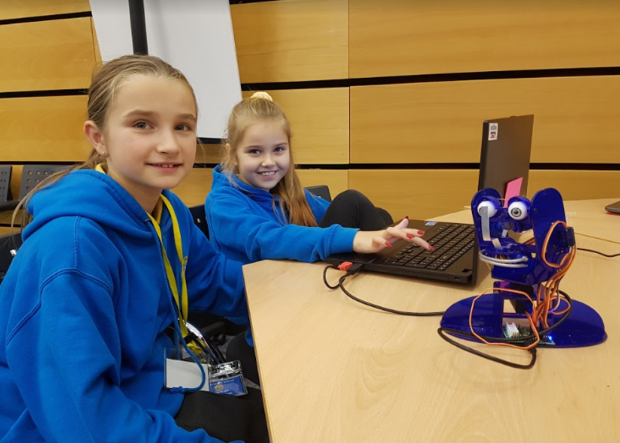 Two girls from Clase Primary School using a laptop to program a robot