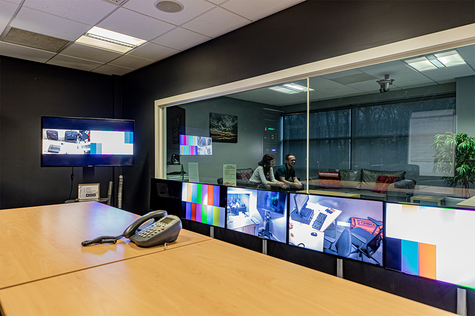 The screens in the UX lab, looking through a one way mirror at a man and a woman talking